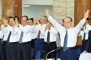 １９９８年９月に行われた本部幹部会の席上、勝利の“Ｖサイン”を掲げ、全同志にエールを送る池田先生（東京牧口記念会館で）