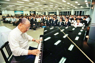 関西創価学園を訪問した池田先生が、「悔いなき充実の青春を」と呼び掛け、ピアノの鍵盤をたたく（１９９５年１０月、交野市で）